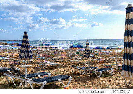 Golden sand beach with empty sun loungers and umbrellas Golden sand beach with empty sun loungers and umbrellas 134430907