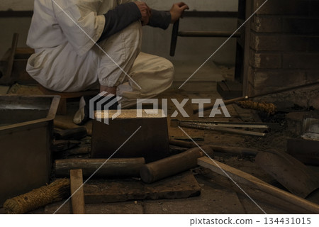 A swordsmith using a bellows in his forge A swordsmith using a bellows in his forge 134431015