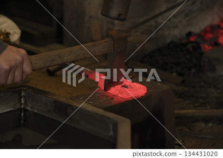 Red-hot steel being folded and forged 134431020