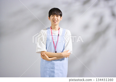 A male nursery teacher in his 20s wearing an apron 134431160