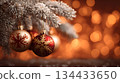 Colorful Christmas ornaments hanging on a snowy tree branch in a warm, festive setting 134433650