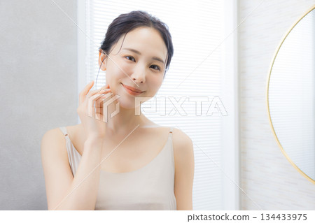 Young woman looking in the mirror in the bathroom 134433975