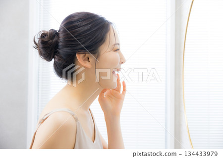 Young woman looking in the mirror in the bathroom 134433979