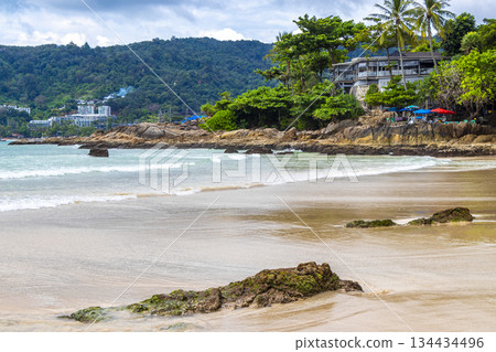 Rocky beach with rocks turquoise water palm trees Patong Thailand. 134434496
