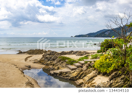 Rocky beach with rocks turquoise water palm trees Patong Thailand. 134434510