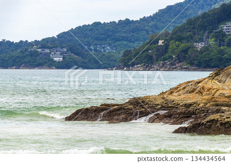 Rocky beach with rocks waves turquoise water in Patong Thailand. Rocky beach with rocks waves turquoise water in Patong Thailand. 134434564