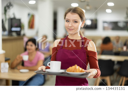 Young female waiter carries order for cafe customer Young female waiter carries order for cafe customer 134435131