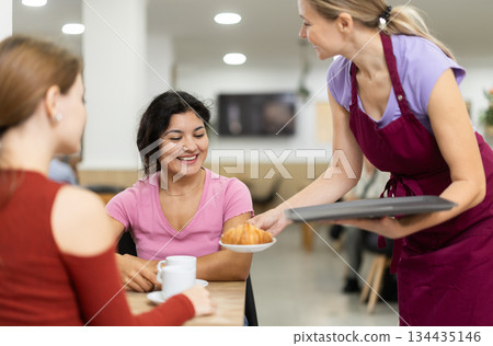 Friendly waitress brought croissants and coffee to female customers 134435146