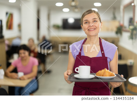 Adult female waiter with tray of coffee and croissant Adult female waiter with tray of coffee and croissant 134435184