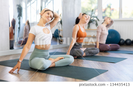Young woman doing neck stretching in Padmasana during yoga training Young woman doing neck stretching in Padmasana during yoga training 134435413