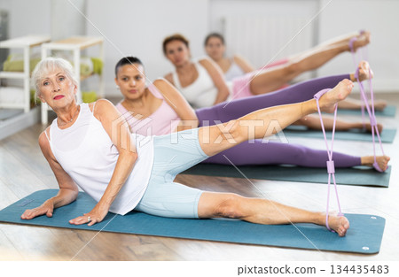 Senior lady doing xercises with figure eight resistance band in studio 134435483