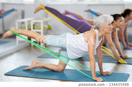 Elderly woman exercises with pilates band Elderly woman exercises with pilates band 134435498