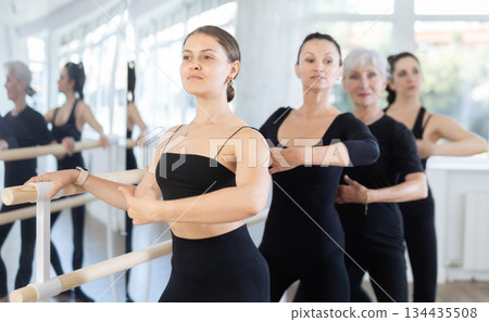 Graceful women of different ages practice at ballet stand in fifth position Graceful women of different ages practice at ballet stand in fifth position 134435508