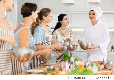 Young lady chef during open culinary lesson tells visitors stages of cooking spicy cream sauce 134435512