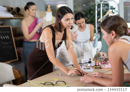 Adult woman teacher explains to group how to draw pattern Adult woman teacher explains to group how to draw pattern 134435517