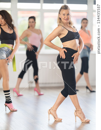 During lesson, woman learn to move and perform dance in heels with women companions 134435587