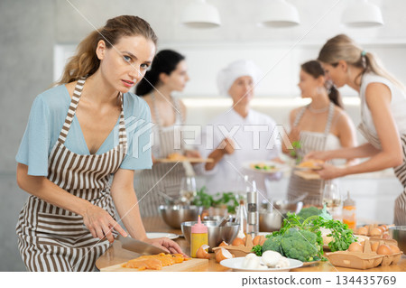 Young woman cutting raw chicken breast Young woman cutting raw chicken breast 134435769