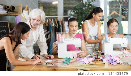 Group of busy women sewing and drawing with teacher at dressmaking courses 134435879
