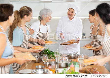 Young woman chef teaches how to cook chicken at master class Young woman chef teaches how to cook chicken at master class 134435929