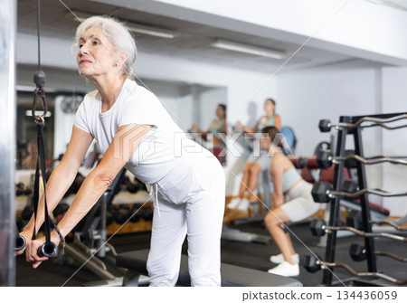 Elderly woman training her arms using straps 134436059
