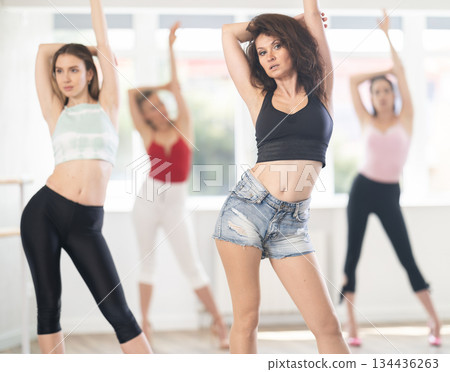 Confident woman leading group heels dance class in studio 134436263