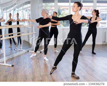 Graceful women of different ages practice various ballet movements in choreographic studio 134436278