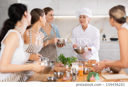Mature female cook holding bowl and whisk 134436281