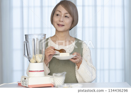 Senior woman making healthy juice with a juicer in the kitchen Senior woman making healthy juice with a juicer in the kitchen 134436296