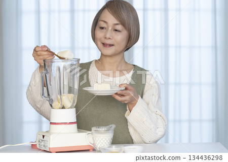 Senior woman making healthy juice with a juicer in the kitchen Senior woman making healthy juice with a juicer in the kitchen 134436298