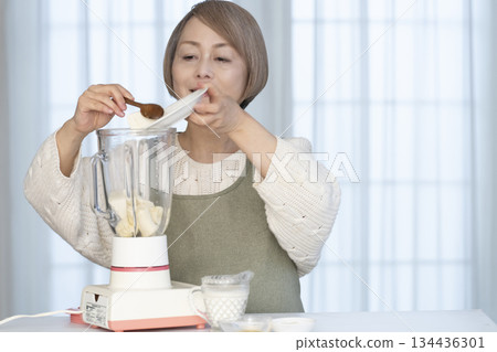 Senior woman making healthy juice with a juicer in the kitchen Senior woman making healthy juice with a juicer in the kitchen 134436301