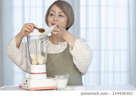 Senior woman making healthy juice with a juicer in the kitchen Senior woman making healthy juice with a juicer in the kitchen 134436302