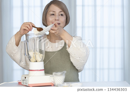 Senior woman making healthy juice with a juicer in the kitchen Senior woman making healthy juice with a juicer in the kitchen 134436303