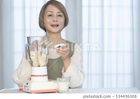 Senior woman making healthy juice with a juicer in the kitchen Senior woman making healthy juice with a juicer in the kitchen 134436308