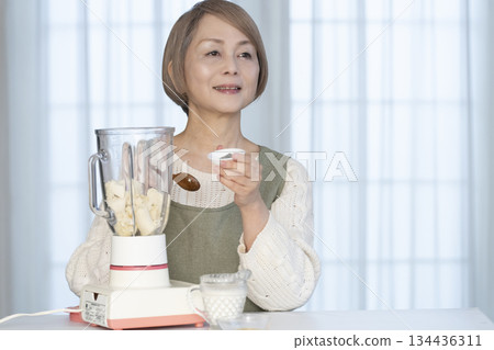 Senior woman making healthy juice with a juicer in the kitchen 134436311
