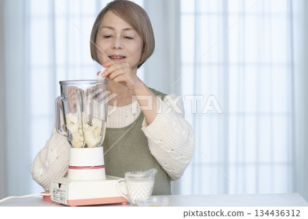 Senior woman making healthy juice with a juicer in the kitchen Senior woman making healthy juice with a juicer in the kitchen 134436312