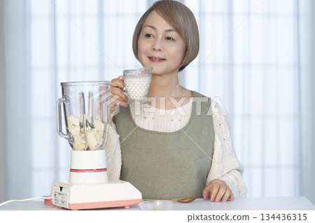 Senior woman making healthy juice with a juicer in the kitchen Senior woman making healthy juice with a juicer in the kitchen 134436315