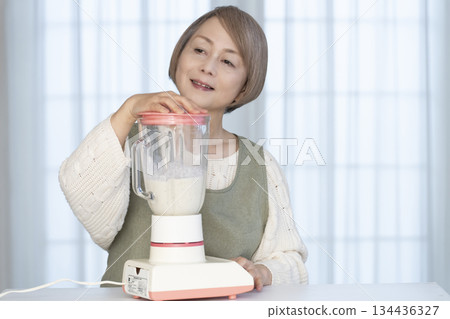 Senior woman making healthy juice with a juicer in the kitchen Senior woman making healthy juice with a juicer in the kitchen 134436327