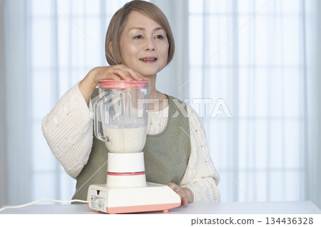 Senior woman making healthy juice with a juicer in the kitchen Senior woman making healthy juice with a juicer in the kitchen 134436328