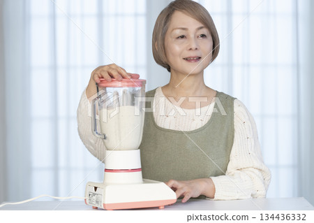 Senior woman making healthy juice with a juicer in the kitchen 134436332