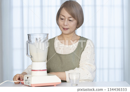 Senior woman making healthy juice with a juicer in the kitchen Senior woman making healthy juice with a juicer in the kitchen 134436333