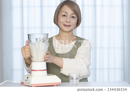 老婦人在廚房用果汁機製作健康果汁 老婦人在廚房用果汁機製作健康果汁 134436334