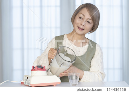 Senior woman making healthy juice with a juicer in the kitchen Senior woman making healthy juice with a juicer in the kitchen 134436336