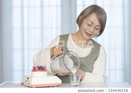 Senior woman making healthy juice with a juicer in the kitchen Senior woman making healthy juice with a juicer in the kitchen 134436338