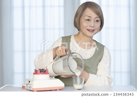 Senior woman making healthy juice with a juicer in the kitchen Senior woman making healthy juice with a juicer in the kitchen 134436343