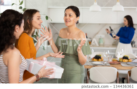 Two women have arrived for birthday celebration and presenting gift to birthday woman 134436361
