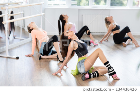 Woman with female perform dance in heels, squat down, actively repeat movements of instructor. 134436420