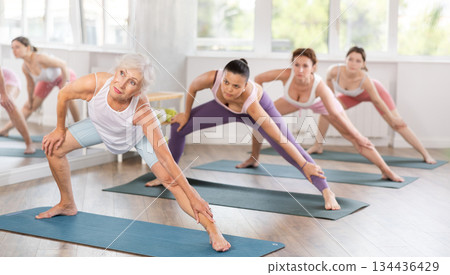 Senior lady performing Side Lunge Pose during group training Senior lady performing Side Lunge Pose during group training 134436429