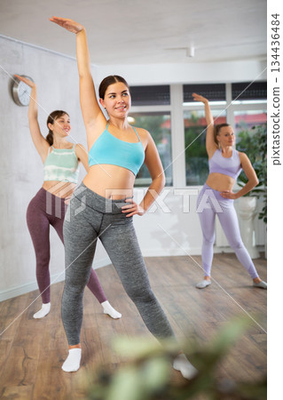 Happy women doing aerobic dances together in dance studio 134436484