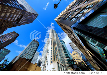 Manhattan skyscrapers rise high against blue sky in urban New York city Manhattan skyscrapers rise high against blue sky in urban New York city 134438149