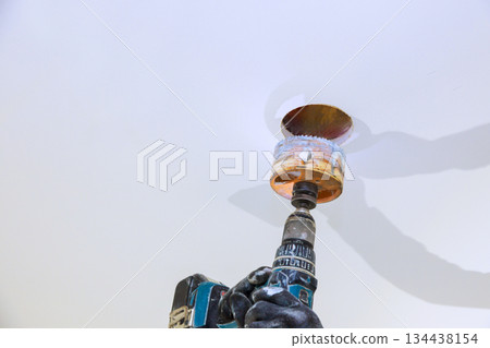 Drilling process in ceiling during home renovation project in bright indoor space 134438154
